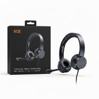 Black over-ear headset with an adjustable boom microphone shown next to its black retail box on a white background. The box features orange text reading 'H12E' and additional product text in German.